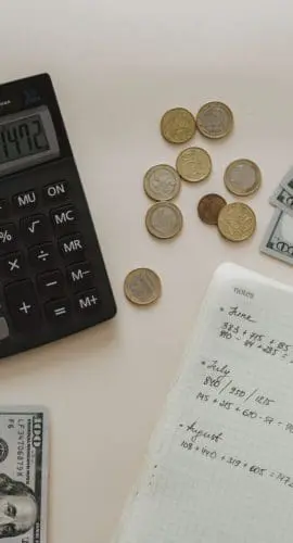 Black calculator beside coins and notebook