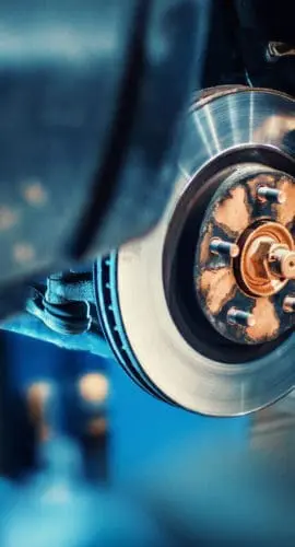 Closeup of unrecognizable mechanic replacing car brake pads. The car is lifted with hydraulic jack at eye level.
