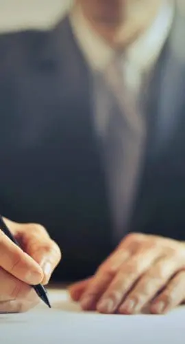 Crop businessman signing contract in office