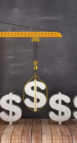 A construction crane is lifting a dollar sign, with three additional dollar signs on the ground beside it.