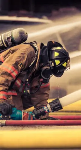 Firefighter holding hose with water flowing