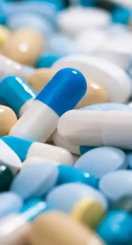 A variety of colorful pills and capsules are scattered closely together.