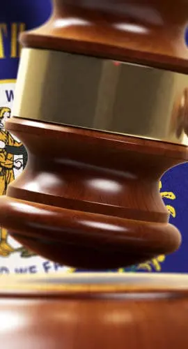 A wooden gavel is poised above a sounding block against a backdrop featuring a seal emblem.