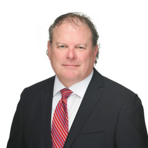 A man in a suit and red-striped tie poses against a white background.
