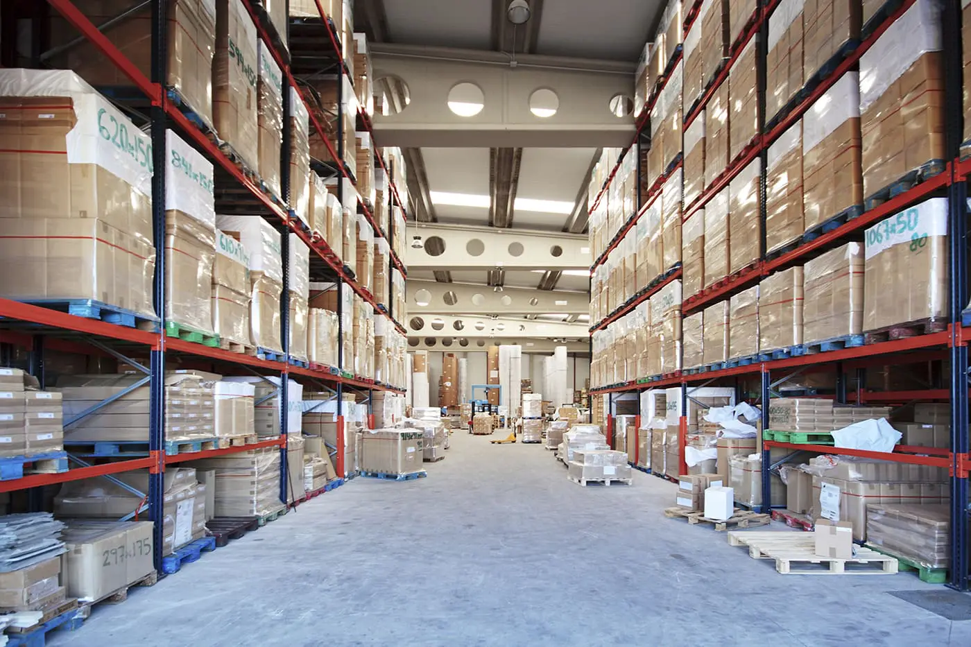 A warehouse interior with tall shelving units stocked with numerous boxes and a central aisle.