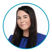 A person with long dark hair is wearing a blue jacket and a slight smile inside a circular blue border.