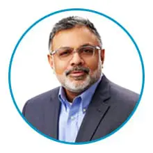 A man with glasses and a beard is wearing a suit and blue shirt, and is framed within a blue circle.