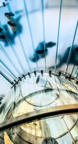 "People walking on transparent glass spiral staircase in futuristic building, unrecognizable people."