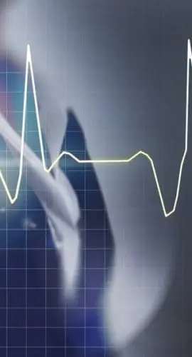 A person in a business suit is pointing at a holographic projection of a heartbeat pulse line chart.