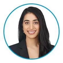 A woman with long dark hair, wearing a black blazer, smiles at the camera within a blue circular frame.