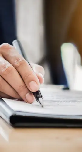 Close-up of a person signing a commercial real estate purchase and sale agreement for a sale-leaseback transaction