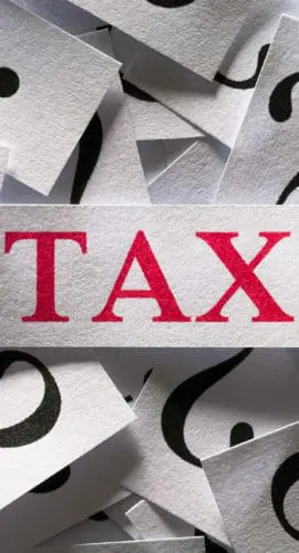 A red "TAX" is surrounded by multiple white cards with black question marks on them.