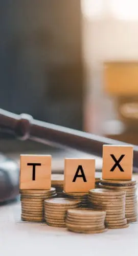 Tax law concept. Wooden blocks word  TAX on coin stack  .with gavel and money on the table.