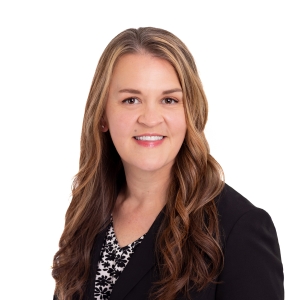 A professional woman is wearing a black blazer over a red top against a white background.